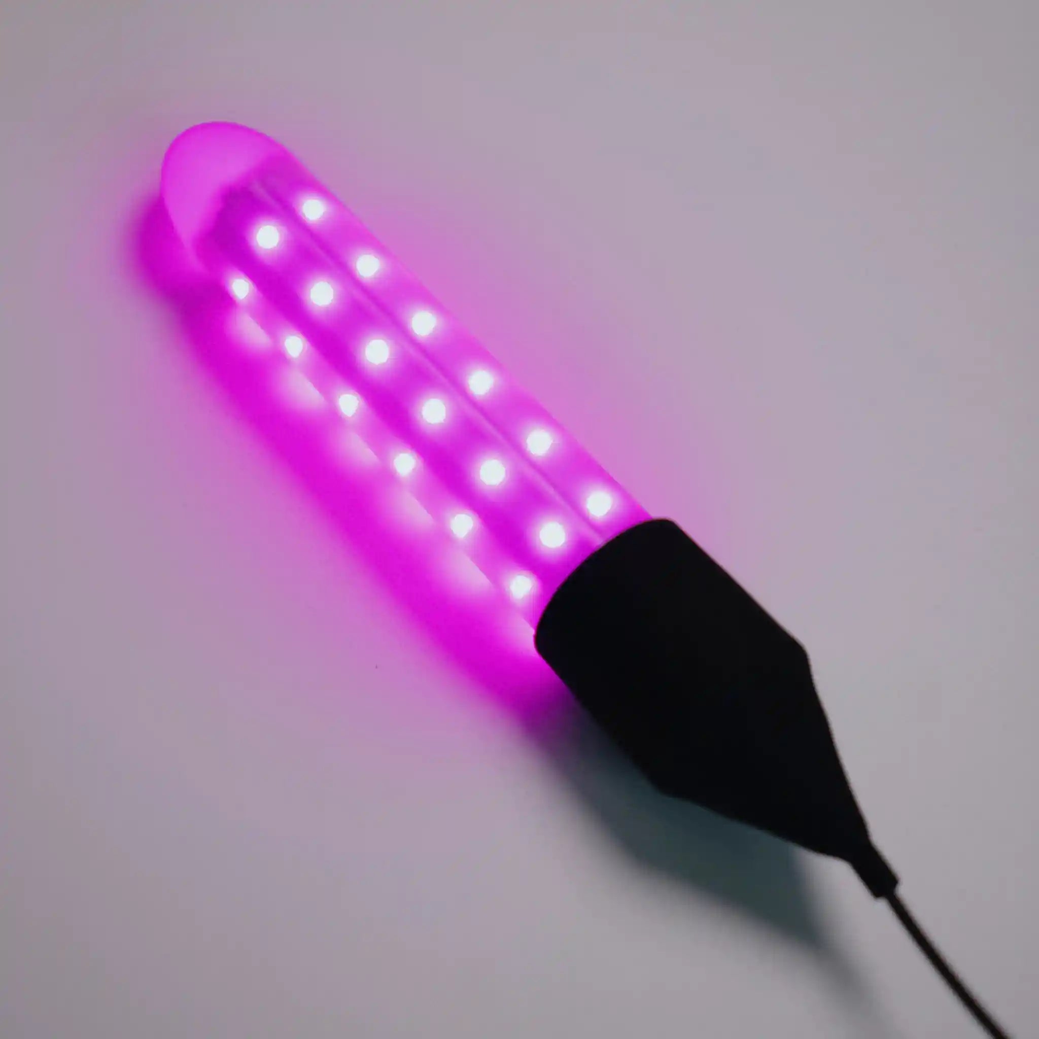 Chroma Purple Wand turned 'on' emitting a pink/purple hue on a grey background