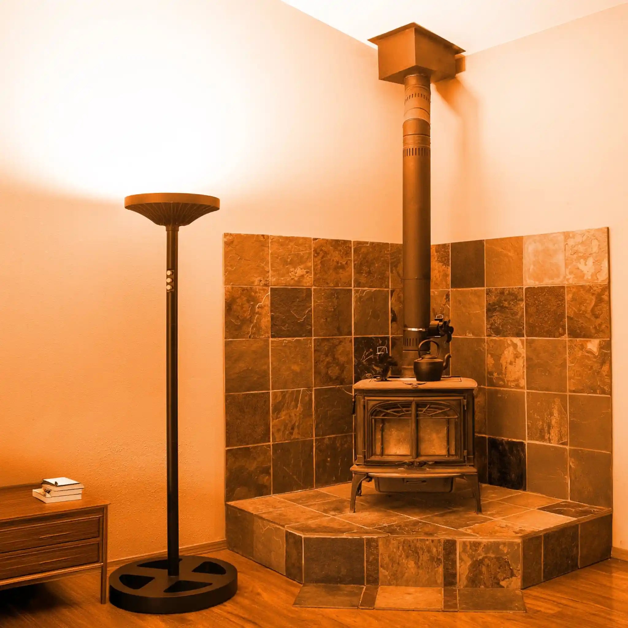 Wood-burning stove in a tiled room with a Chroma skylight tall floor lamp positioned next to it creating an amber tone.