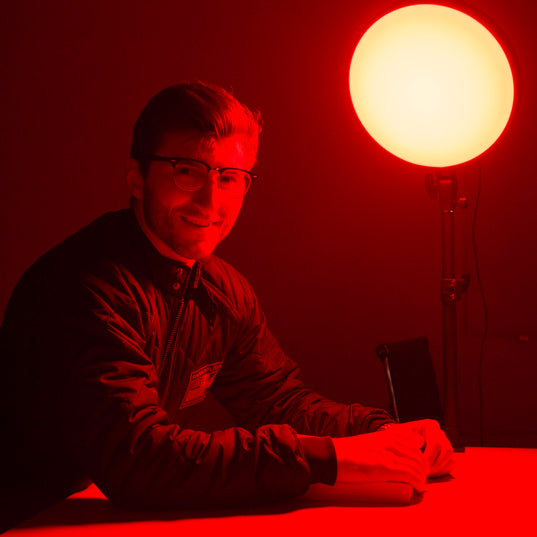 Person sitting at a table with a red light source from a Chroma Red Portal in a dark room