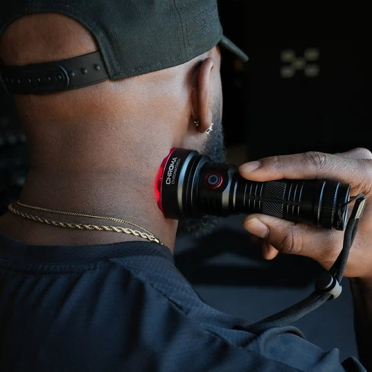 Person holding a torch (Chromatorch) with a Chroma brand logo, wearing a cap and dark clothing pressing the torch against their neck.