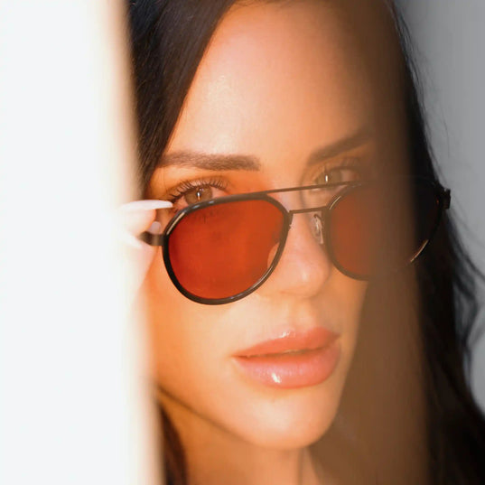 Close-up of a woman wearing Chroma Nightshades red-tinted glasses with a bright light in the foreground