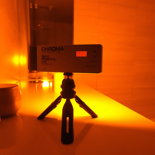 Chroma Sky Portal Mini device on a tripod in an orange-lit room.